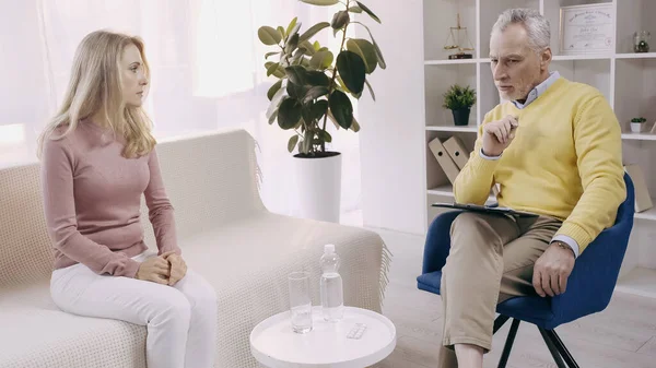 Pensive and mature psychologist having conversation with blonde patient — Stock Photo