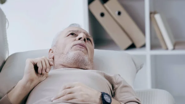 Homme mature déprimé couché sur le canapé et parlant dans la salle de consultation — Photo de stock