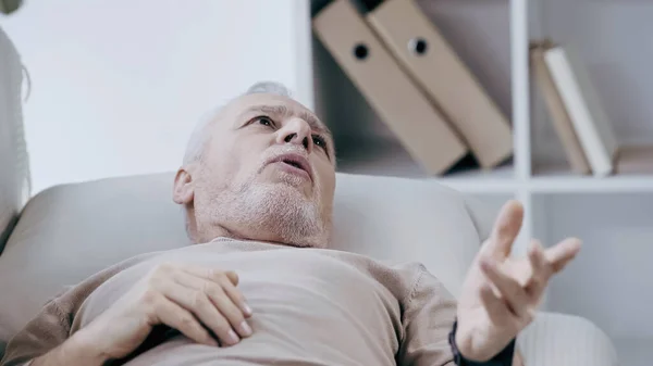 Депресивний чоловік середнього віку лежить на дивані і говорить в консалтинговій кімнаті — стокове фото