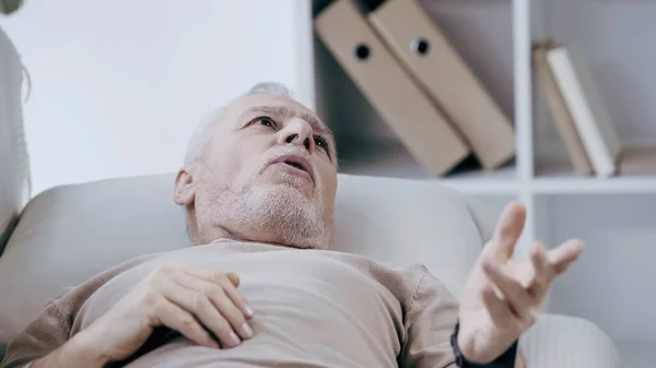 Depressed middle aged  man lying on couch and talking in consulting room — Stock Photo