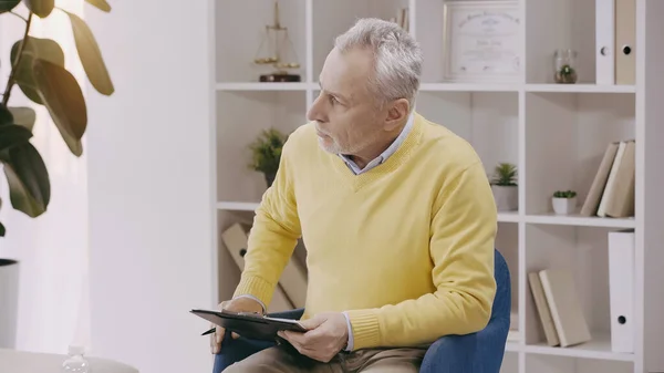 Mature psychologist holding clipboard during consultation — Fotografia de Stock