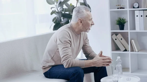 Worried mature man talking in consulting room during psychotherapy — Stock Photo