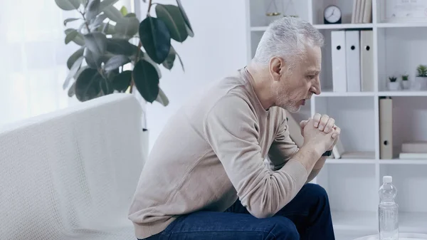 Side view of upset middle aged man talking in consulting room during psychotherapy — Fotografia de Stock