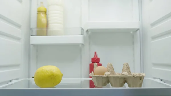 Whole lemon, egg, bottles with mayonnaise, mustard and tomato sauce in refrigerator — Fotografia de Stock