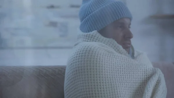 Sick man in warm hat and blanket sitting on couch at home — Fotografia de Stock