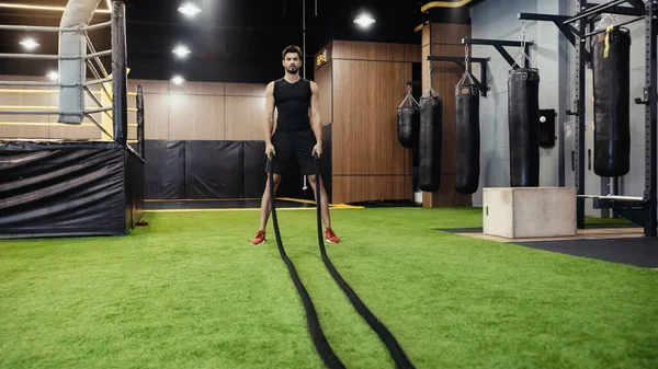 Full length of bearded man working out with battle ropes — Stock Photo
