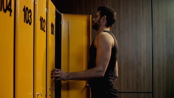 Bearded sportsman opening door in locker room — Stockfoto