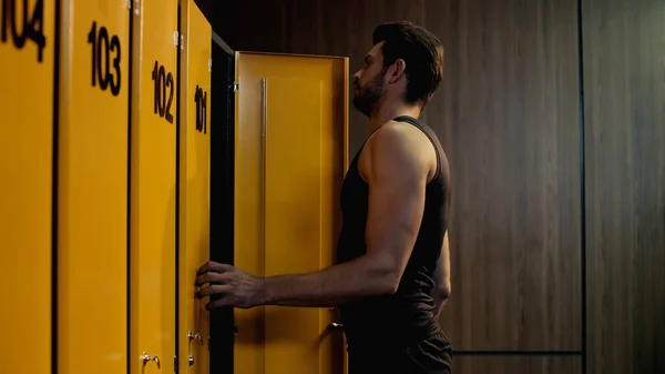 Bearded sportsman opening door in locker room — Stock Photo