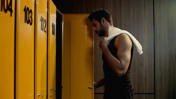 Side view of bearded sportsman taking towel in locker room — Stock Photo