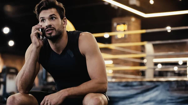 Young sportsman talking on smartphone in gym — Stock Photo