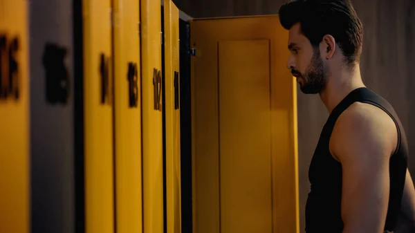 Side view of bearded sportsman standing in locker room - foto de stock