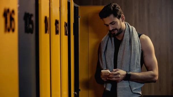 Happy sportsman messaging on smartphone in locker room — Photo de stock