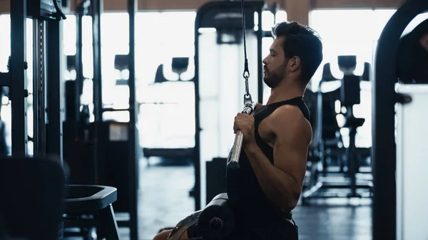 Side view of sportsman training on fitness machine in gym — Stock Photo