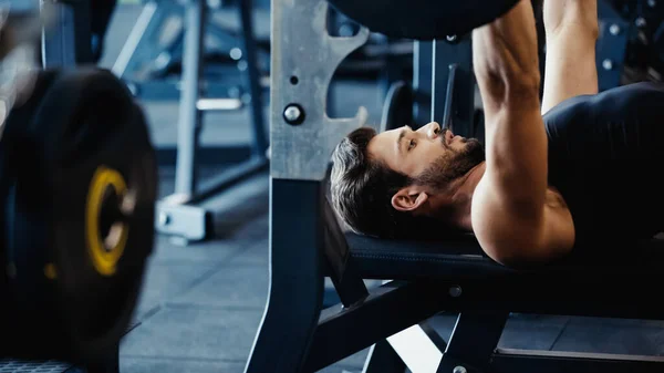 Strong and bearded sportsman weightlifting barbell in gym — Fotografia de Stock