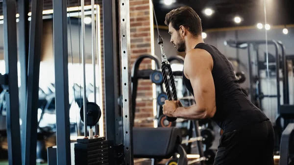 Deportista barbudo haciendo ejercicio en la máquina de fitness en el centro deportivo - foto de stock