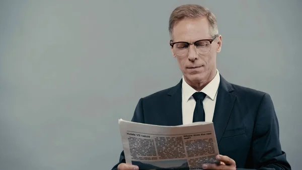 Empresario en anteojos leyendo periódico aislado en gris - foto de stock