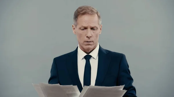 Бізнесмен дивиться на папери ізольовані на сірому — стокове фото