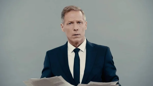 Middle aged businessman holding papers and looking at camera isolated on grey — Stock Photo