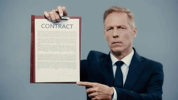 Mature businessman pointing at contract on clipboard isolated on grey — Stock Photo