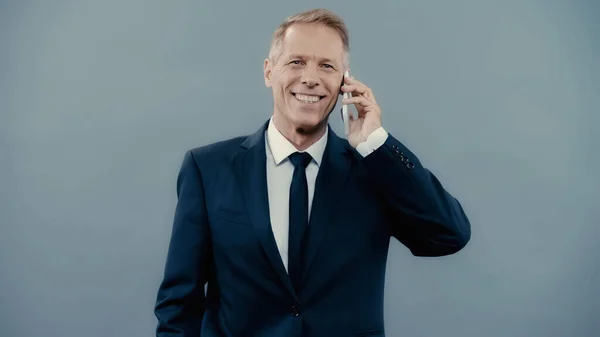 Cheerful businessman talking on mobile phone isolated on grey — Stock Photo