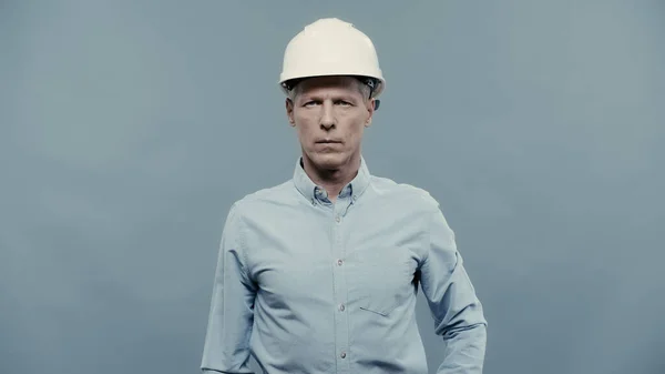 Mature engineer in protective helmet looking at camera isolated on grey — Fotografia de Stock