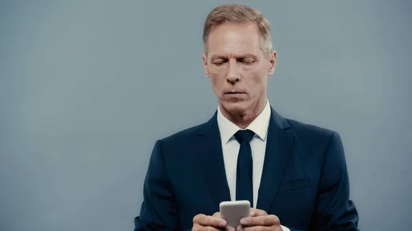 Зрілий бізнесмен у костюмі спілкування на смартфоні ізольовано на сірому — стокове фото