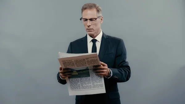 Зрілий менеджер в окулярах читає новини ізольовані на сірому — стокове фото