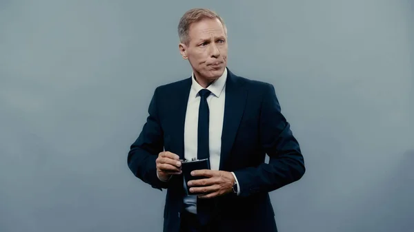 Businessman holding drinking flask and looking away isolated on grey — Stock Photo