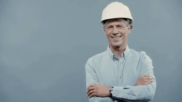 Positive engineer in hardhat crossing arms isolated on grey — Stock Photo