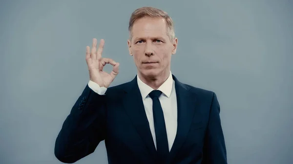 Mature businessman in formal wear showing okay gesture isolated on grey — Stock Photo