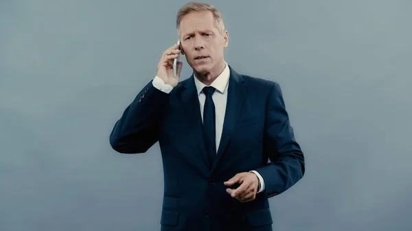 Homme d'affaires stressé parlant sur téléphone portable isolé sur gris — Photo de stock