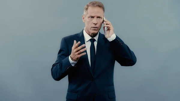 Зрілий менеджер говорить на мобільному телефоні ізольовано на сірому — стокове фото