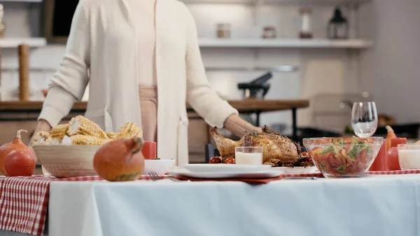 Cropped view of blurred woman standing near festive dinner served for thanksgiving — стоковое фото