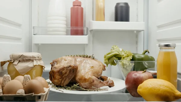 Roasted turkey prepared for thanksgiving dinner near fresh vegetables, fruits and containers with food in fridge — Stock Photo