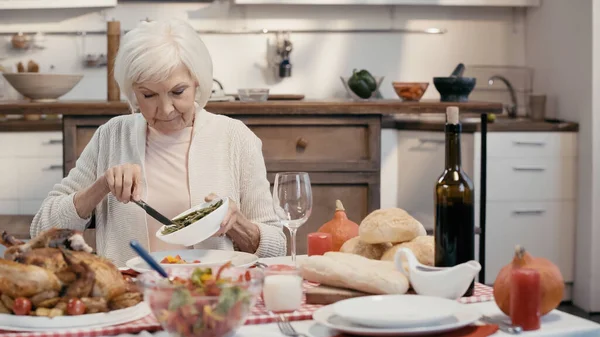 Senior femme avec les cheveux gris ayant thanksgiving dîner dans la cuisine — Photo de stock