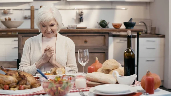 Femme âgée étonnante souriant près de délicieux dîner servi pour thanksgiving — Photo de stock