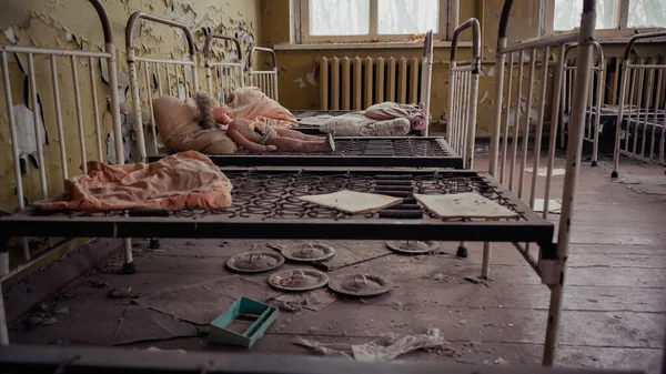 Abandoned kindergarten with metal beds, dirty pillows, papers and broken doll in chernobyl — Photo de stock