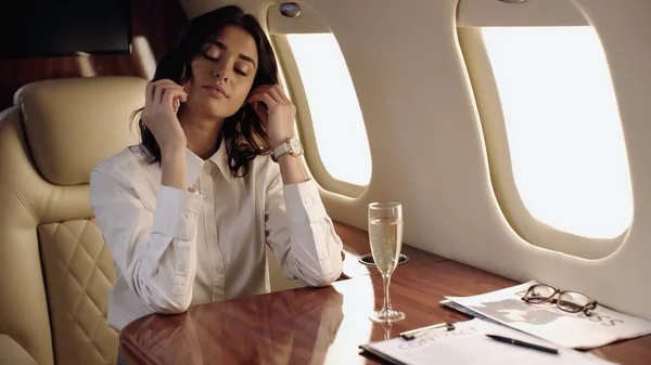 Femme d'affaires assise près de champagne et journal en jet privé — Photo de stock