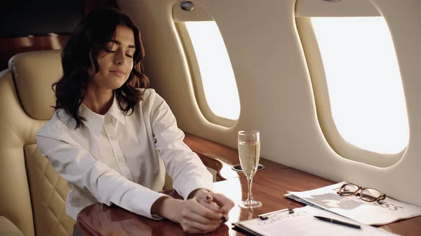 Молода бізнес-леді, що сидить біля шампанського і газети в приватному літаку — стокове фото