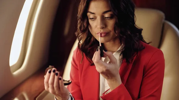 Femme d'affaires appliquant gloss lèvre dans l'avion privé — Photo de stock