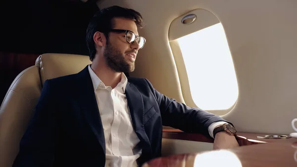 Smiling businessman in eyeglasses sitting in private plane — Stock Photo