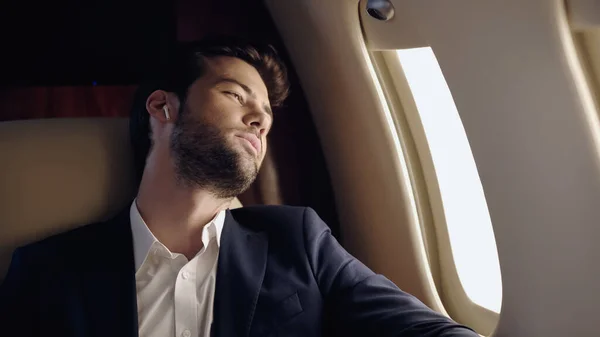 Businessman in formal wear and earphone in private plane — Stock Photo