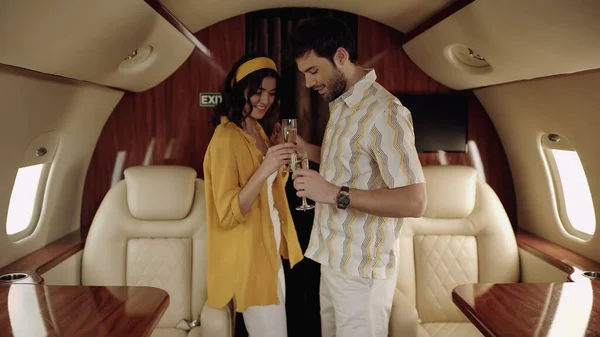 Smiling couple holding glasses of champagne in private jet — Stock Photo