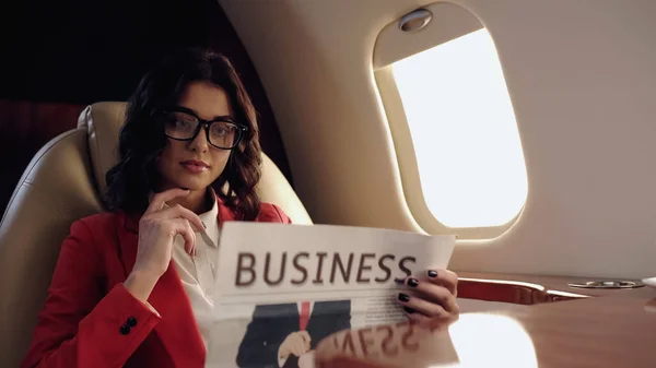 Young businesswoman reading blurred newspaper in private plane — Stock Photo