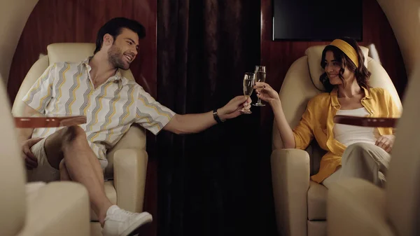 Smiling couple clinking champagne in private jet — Stock Photo