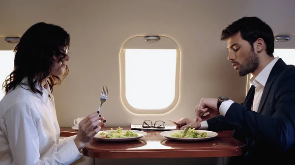 Business people sitting near fresh salads in private jet — Stock Photo