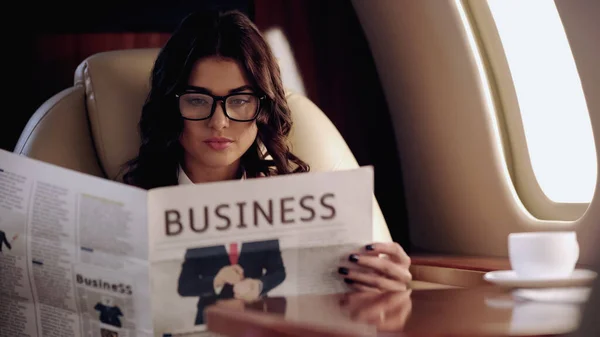 Businesswoman reading news near cup of coffee on table in private plane — Fotografia de Stock