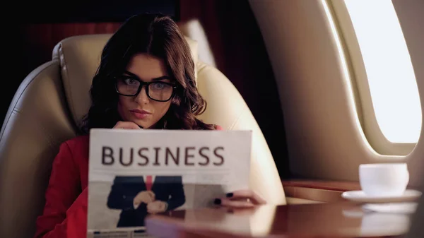 Focused businesswoman reading newspaper in private plane — Stockfoto