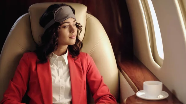 Young businesswoman in sleep mask near cup in private plane — Foto stock