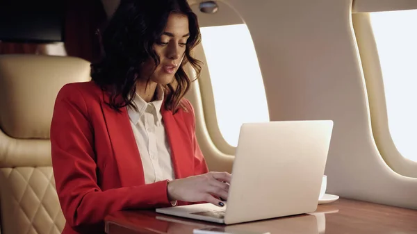 Молода бізнес-леді використовує ноутбук у приватному реактивному літаку — стокове фото
